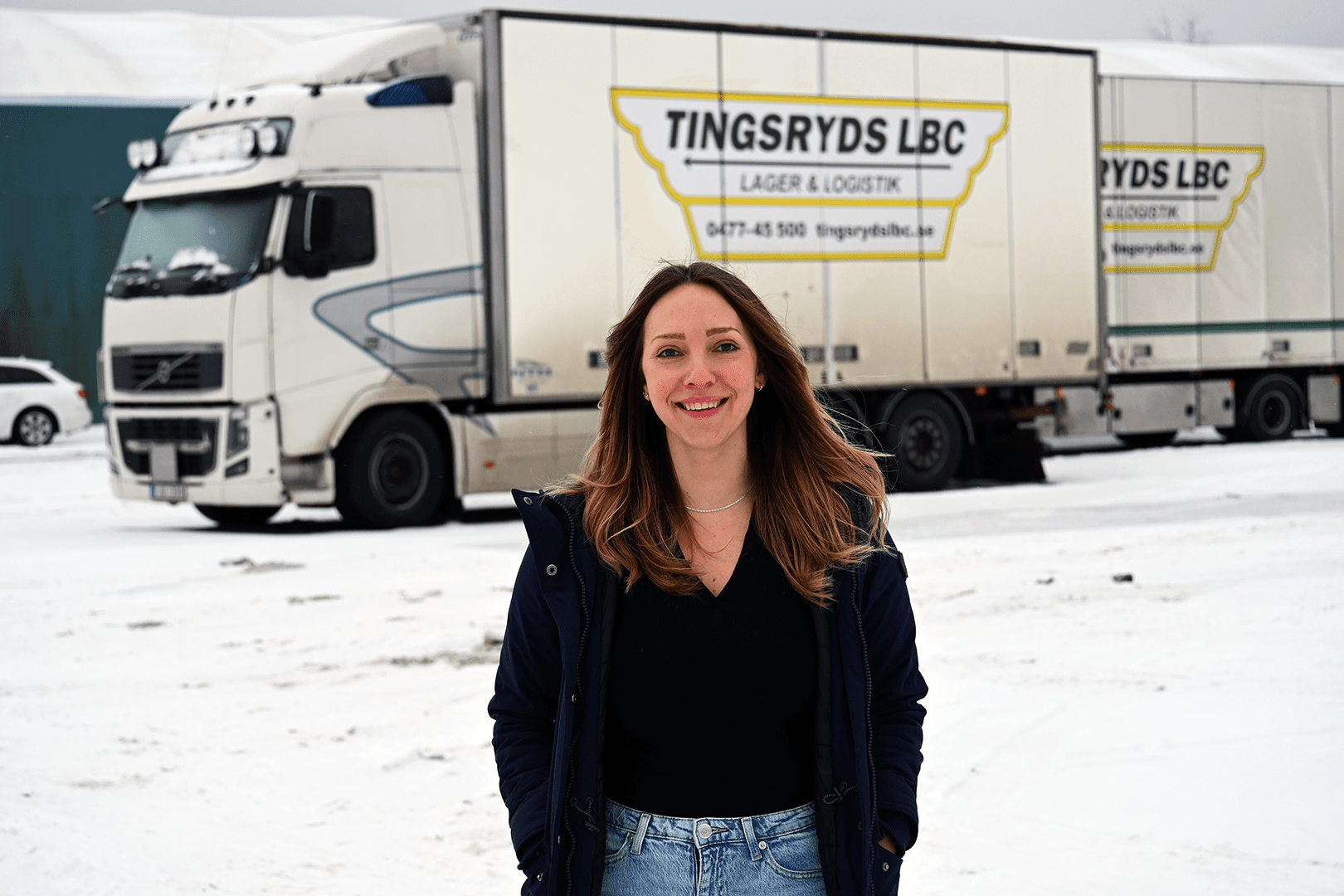 Porträttbild av Linn va der Hoek Karlsson framför en av Tingsryds LBC lastbilar
