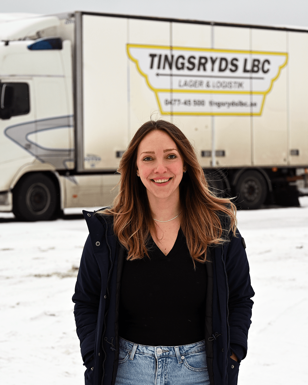 Porträttbild av Linn va der Hoek Karlsson framför en av Tingsryds LBC lastbilar